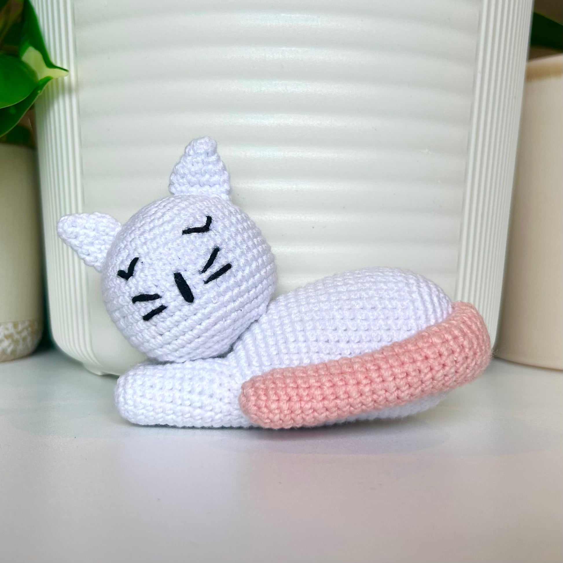 White crocheted sleeping cat with a light melon colored tail