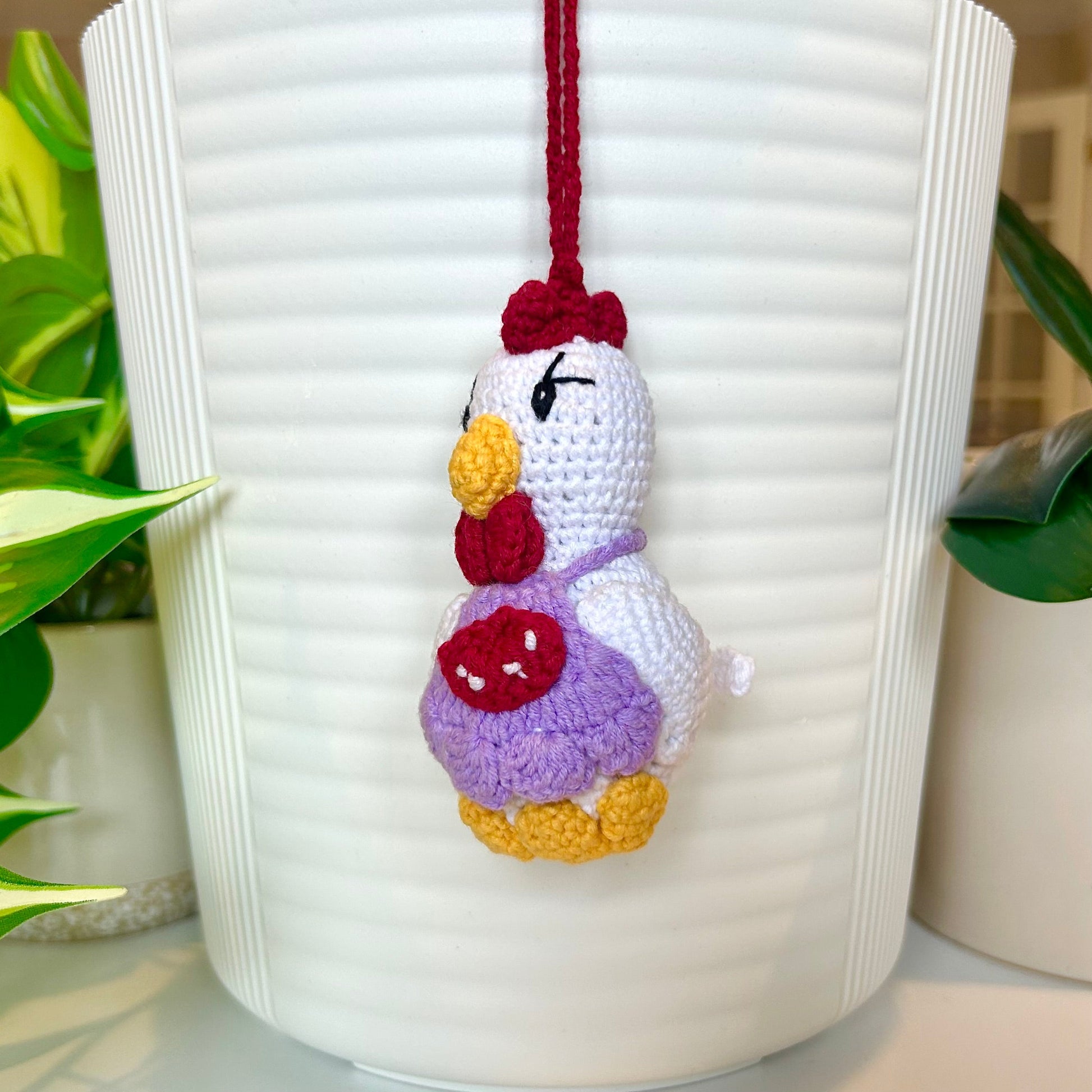 white crocheted chicken charm wearing a lavender apron with red and white accents