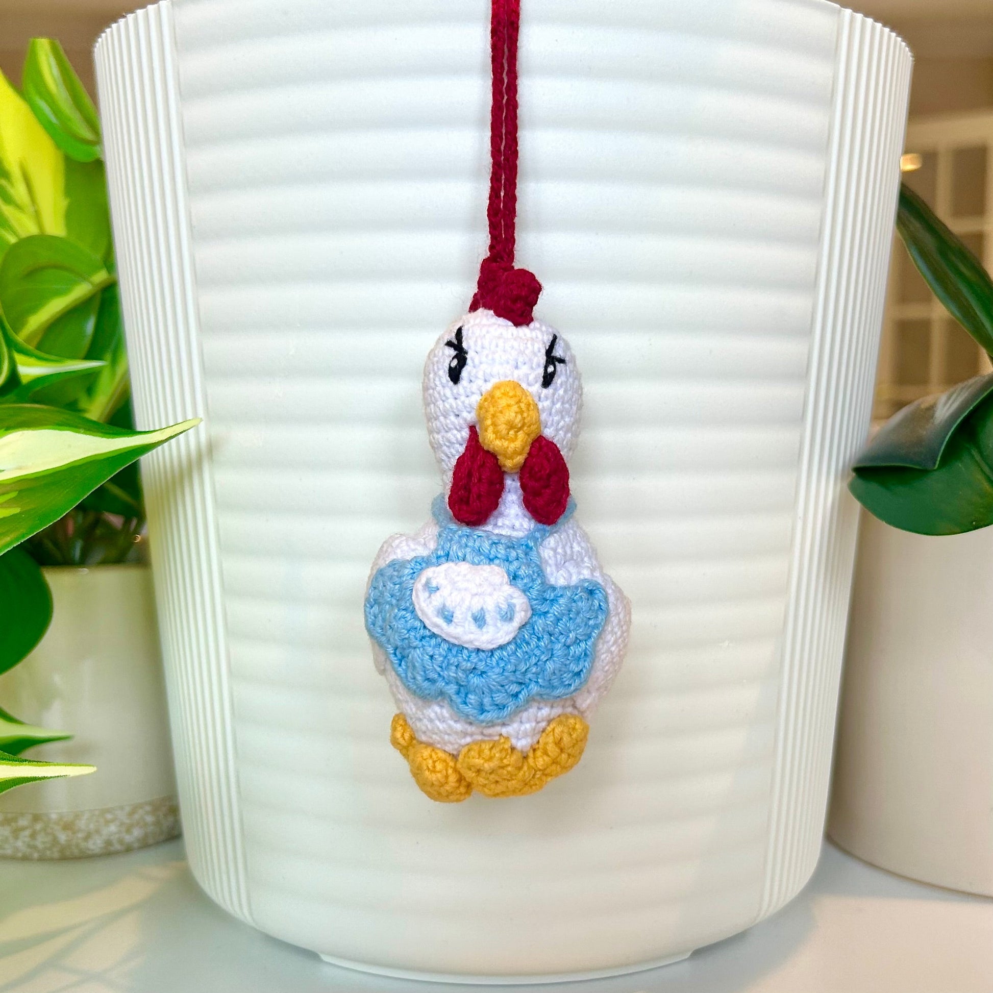 White crocheted chicken charm wearing a sky blue apron 