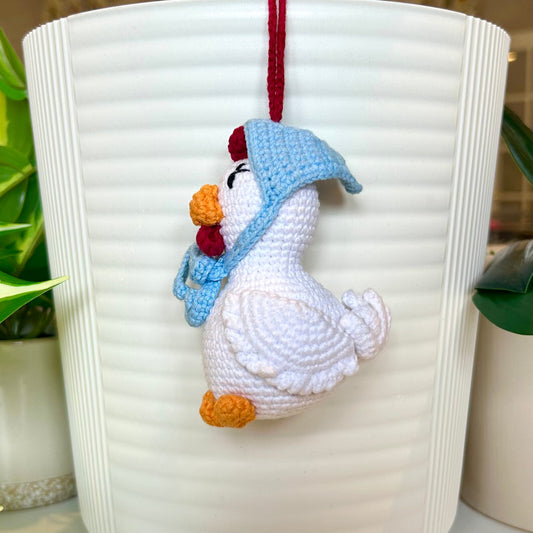 Right side profile of white crocheted chicken charm with red comb and a sky blue kerchief