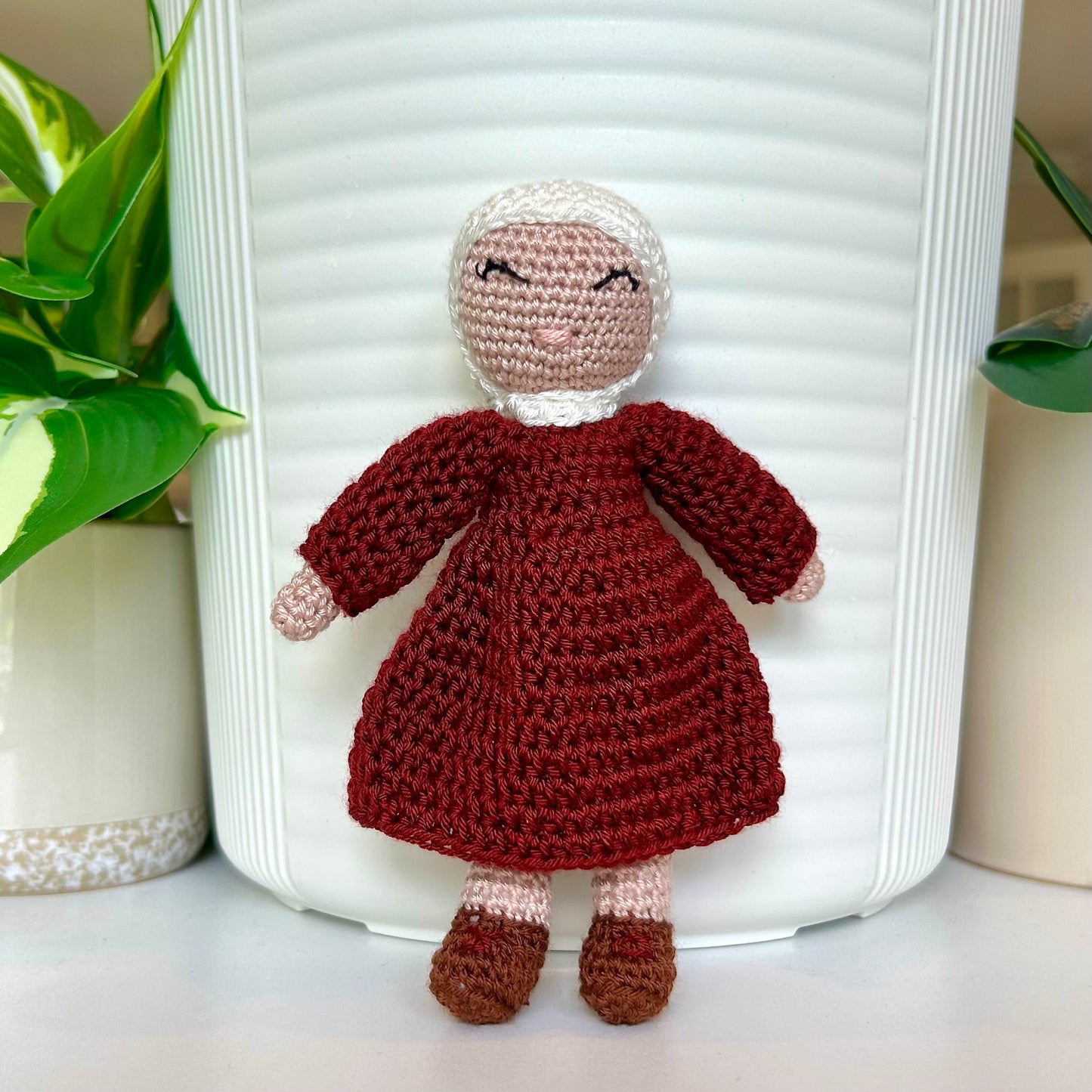 Crocheted doll wearing a white hijab and burgundy dress