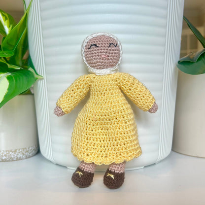 Crocheted doll wearing a white hijab and a cream brulee colored dress