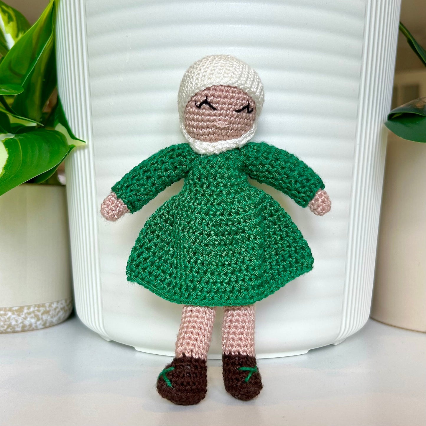 Crocheted doll wearing a white hijab and a jade green dress
