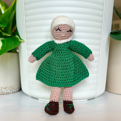 Crocheted doll wearing a white hijab and a jade green dress