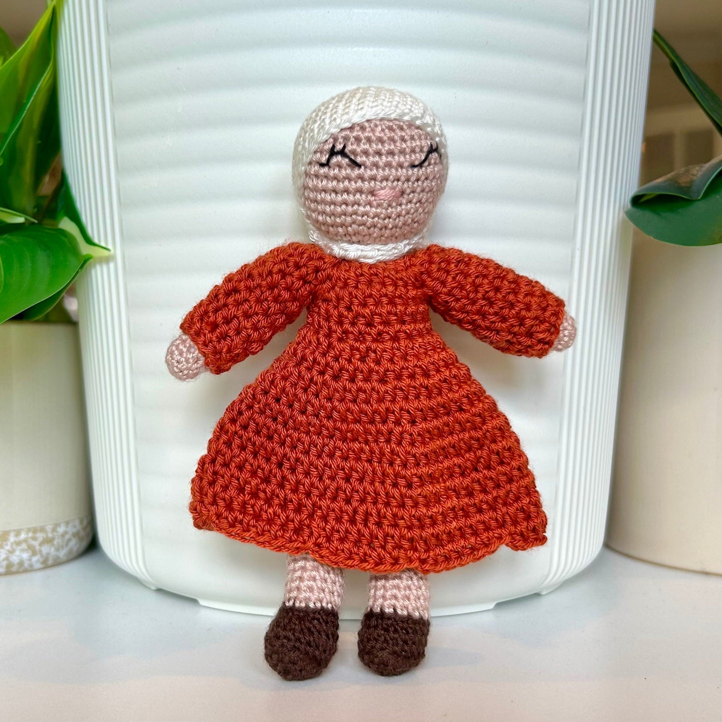 Crocheted doll wearing a white hijab and a terracotta dress