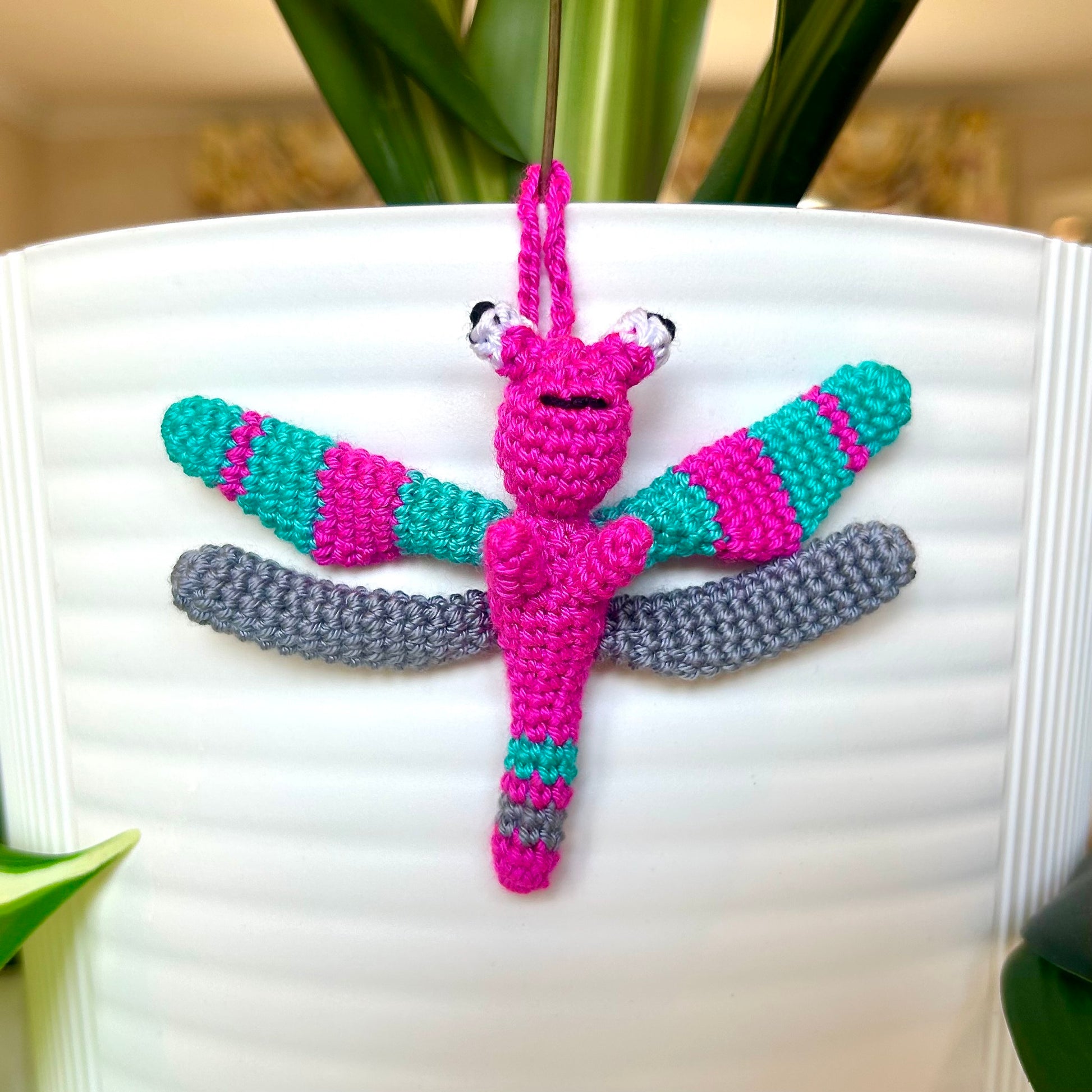 Mini crocheted dragonfly charm with hot pink, teal, and gray stripes