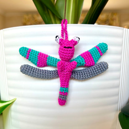 Mini crocheted dragonfly charm with hot pink, teal, and gray stripes