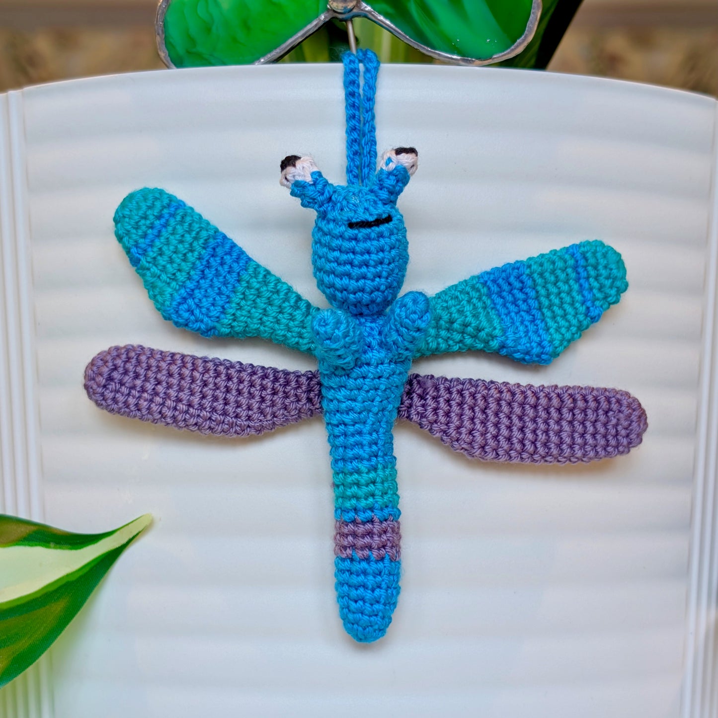Small crocheted dragonfly bag charm with azure, purple, and teal stripes
