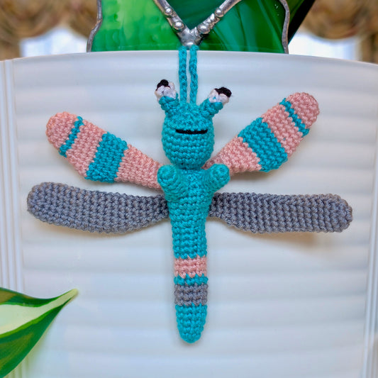 Small crocheted dragonfly bag charm with teal, pink, and gray stripes