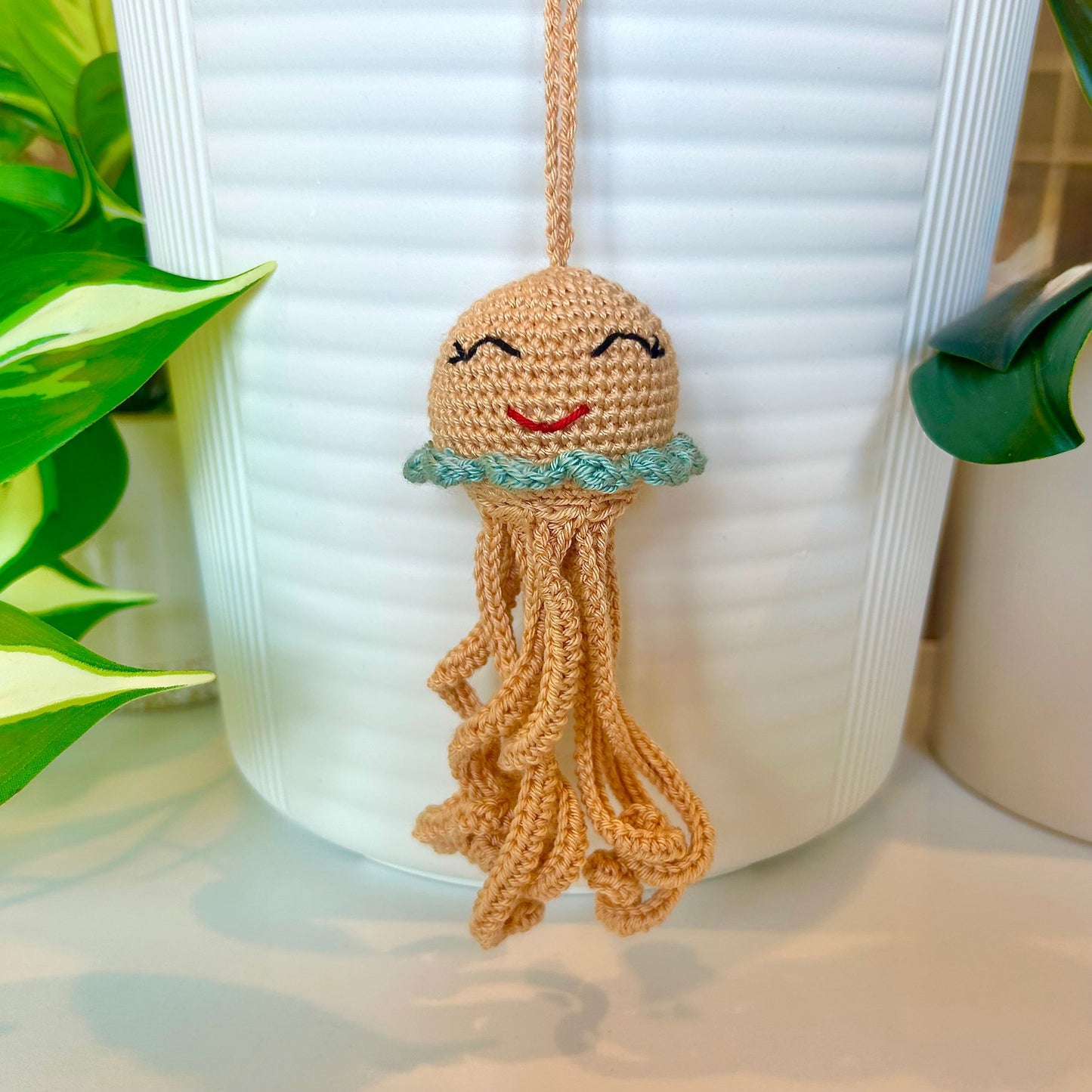 Crocheted caramel-colored jellyfish bag charm with seafoam blue trim