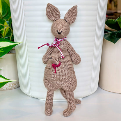 Crocheted kangaroo wearing a berry and white scarf with a baby joey in her pouch wearing a berry scarf