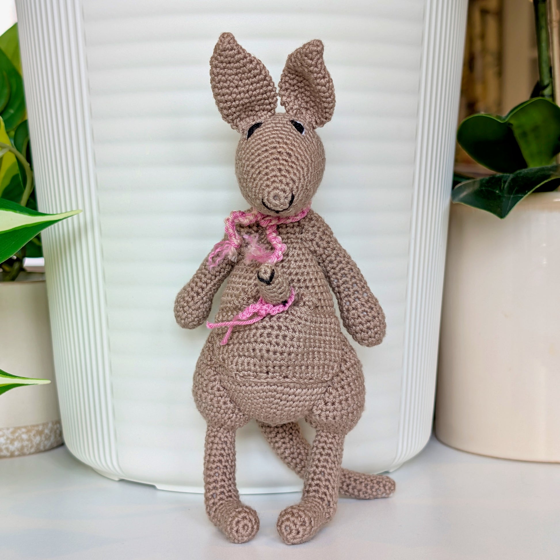 Crocheted kangaroo wearing a light orchid and soft melon scarf with a baby joey in her pouch wearing a light orchid scarf