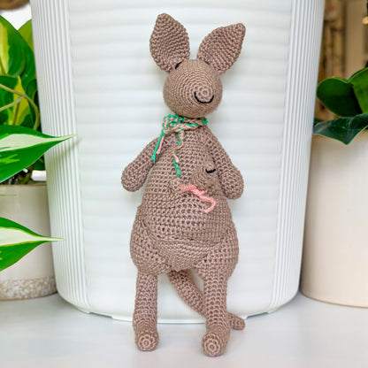Crocheted kangaroo wearing an emerald and melon pink scarf with a baby joey in her pouch wearing a melon pink scarf