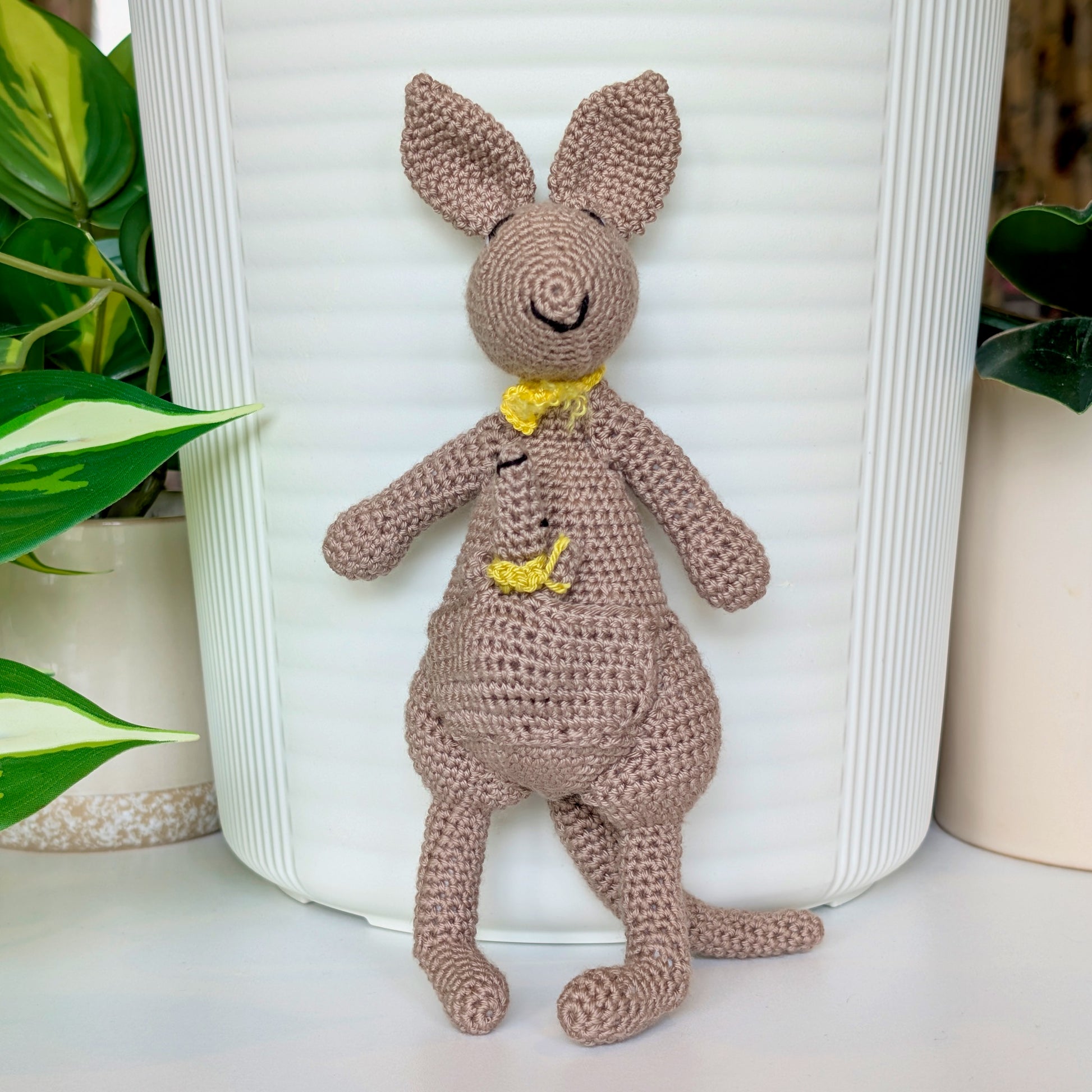 Crocheted kangaroo wearing a yellow scarf with a baby joey in her pouch wearing a chartreuse scarf