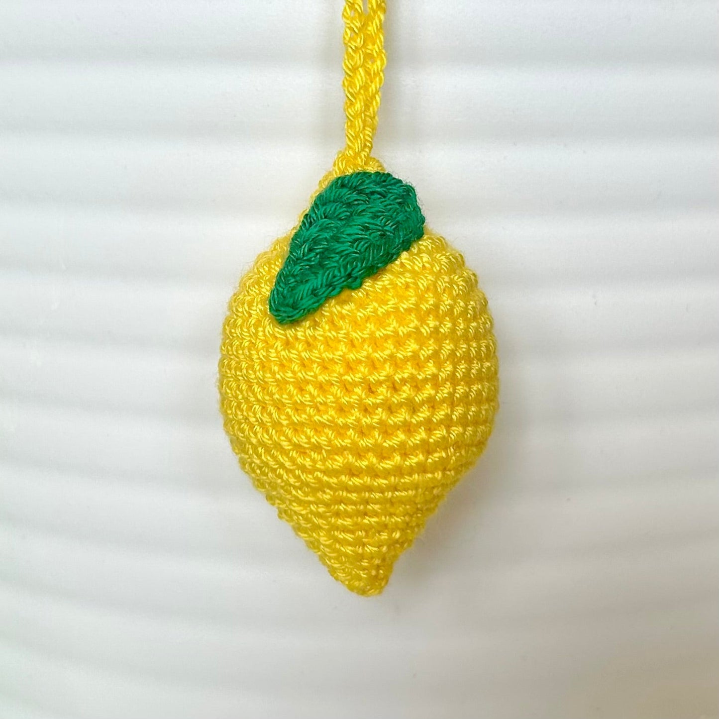 crocheted yellow lemon keychain with a green leaf