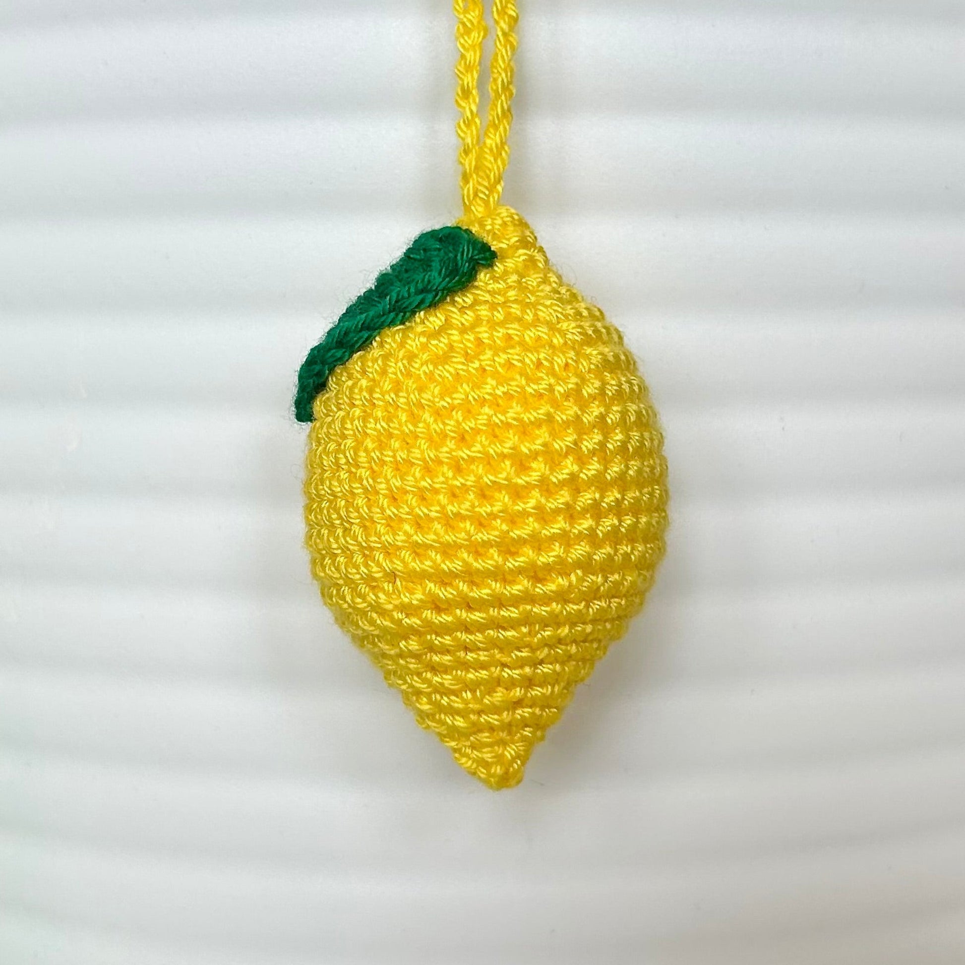 crocheted yellow lemon keychain with a green leaf