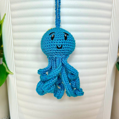 Crocheted octopus charm in azure blue with a small chartreuse flower on its head