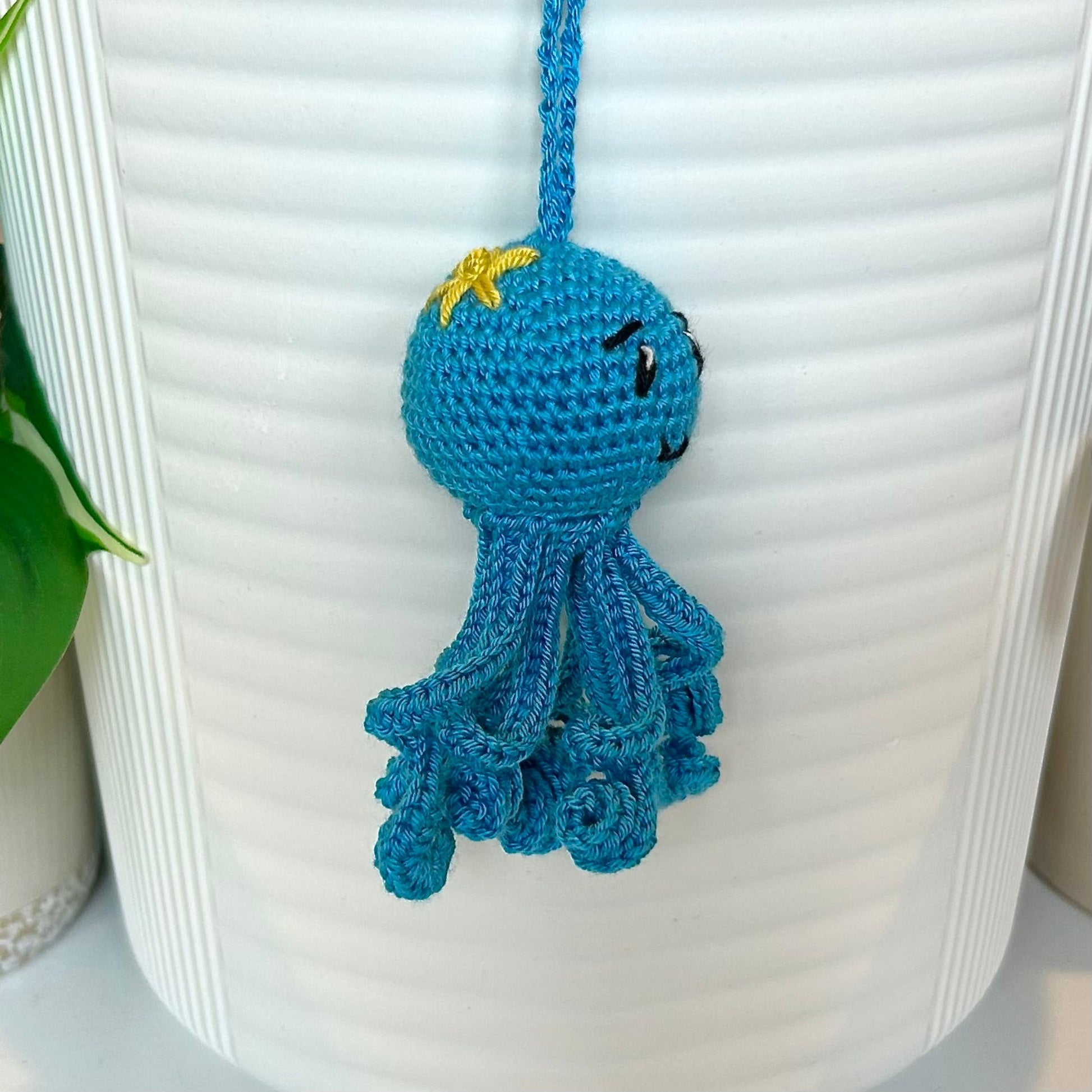 Right side profile of Octopus charm in azure blue with a small chartreuse flower on its head
