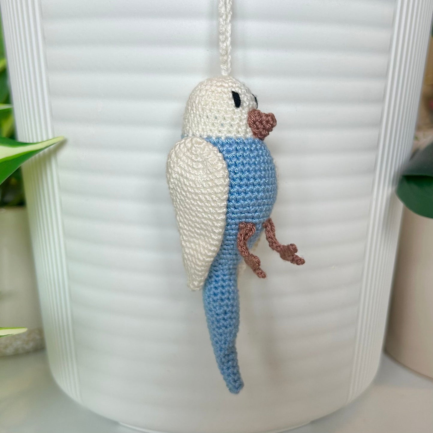 Right side profile of Crocheted parakeet charm with white wings and body and light blue body