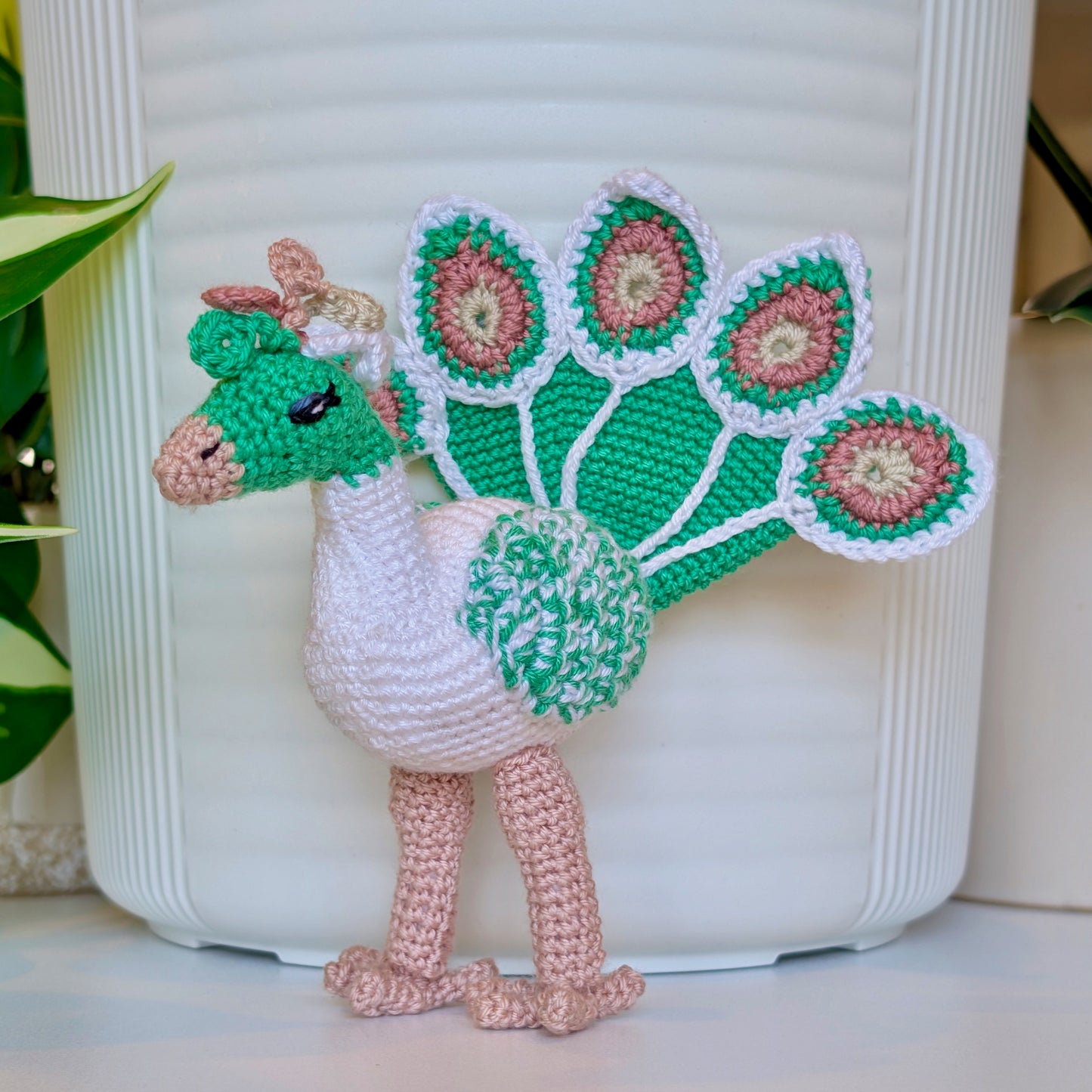 white crochet peacock with emerald green and pastel rose accents