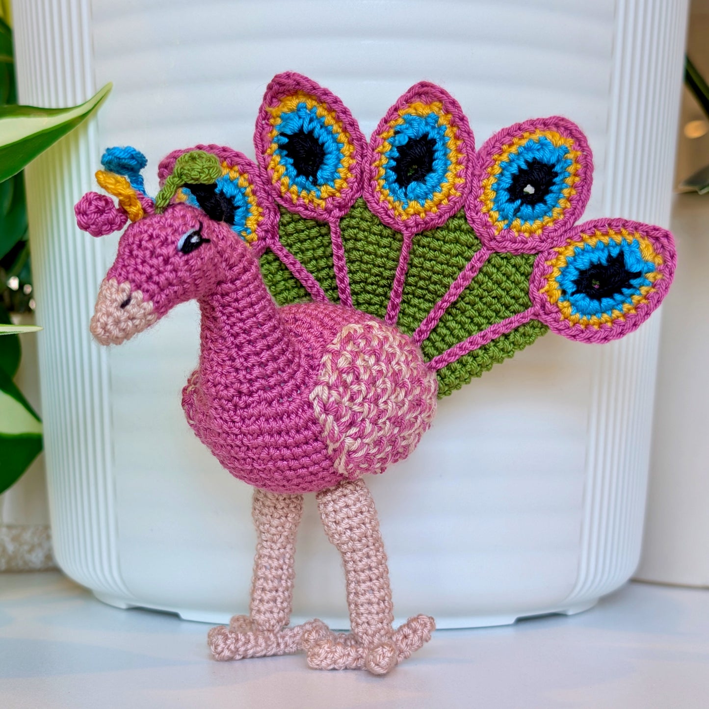 Crochet peacock in Wild Orchid with Moss Green, Caribbean Blue, and Sunflower Yellow accents