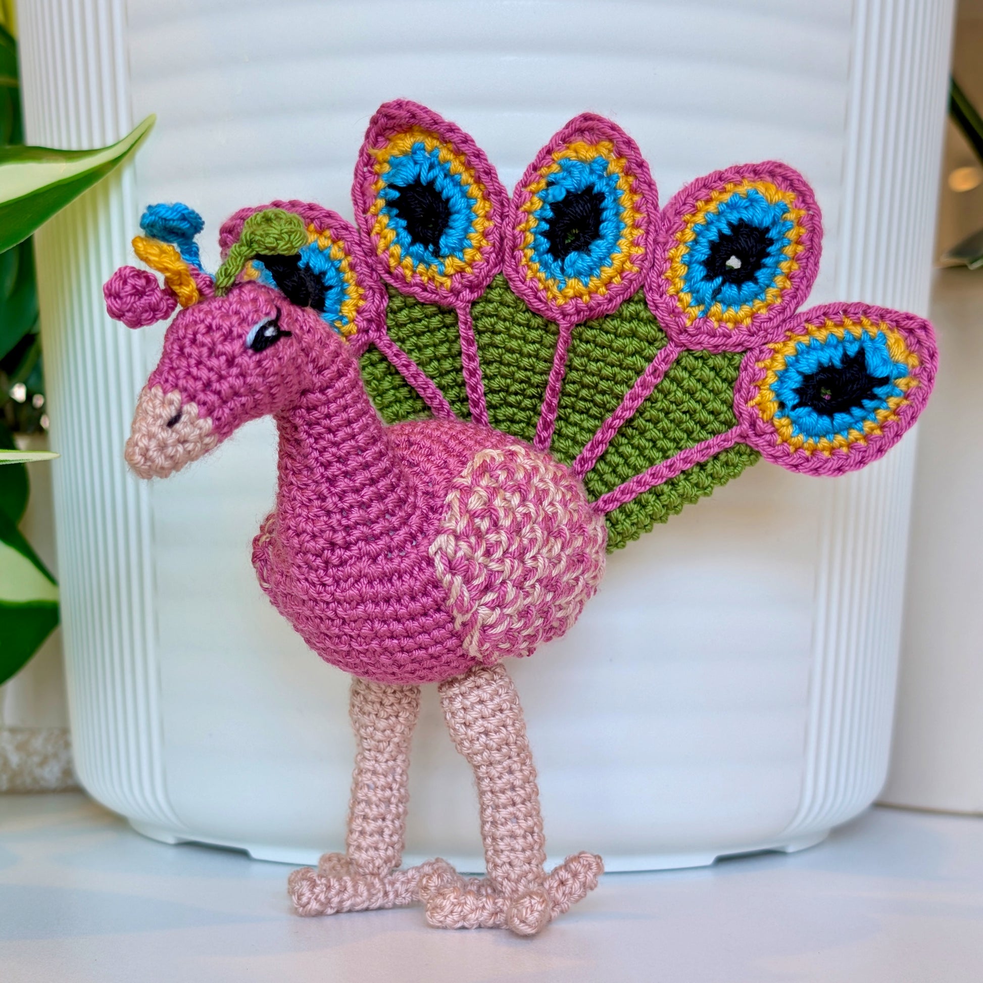 Crochet peacock in Wild Orchid with Moss Green, Caribbean Blue, and Sunflower Yellow accents