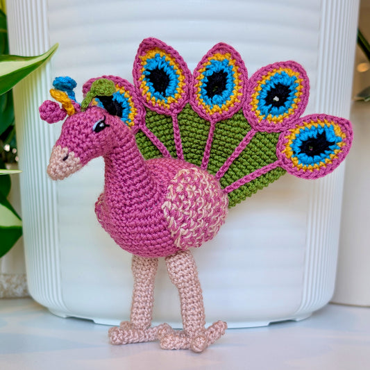 Crochet peacock in Wild Orchid with Moss Green, Caribbean Blue, and Sunflower Yellow accents
