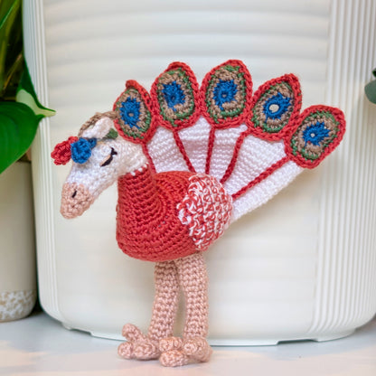 crochet peacock in watermelon red with White, Peacock Blue, and dark Sage accents