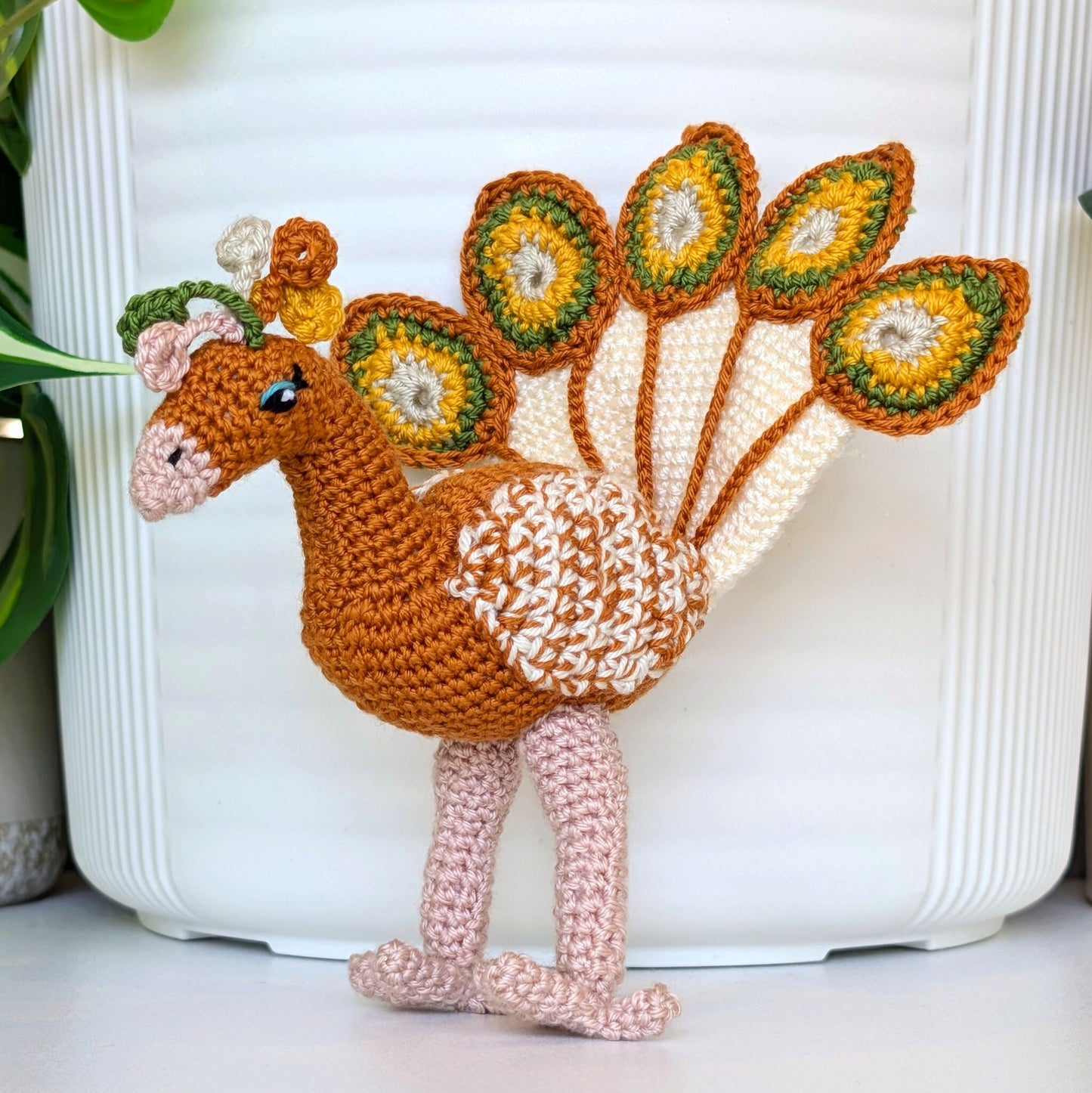 Gold colored crochet peacock with white, sunflower yellow, and moss green accents