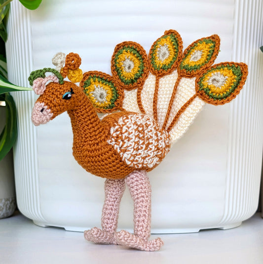 Gold colored crochet peacock with white, sunflower yellow, and moss green accents