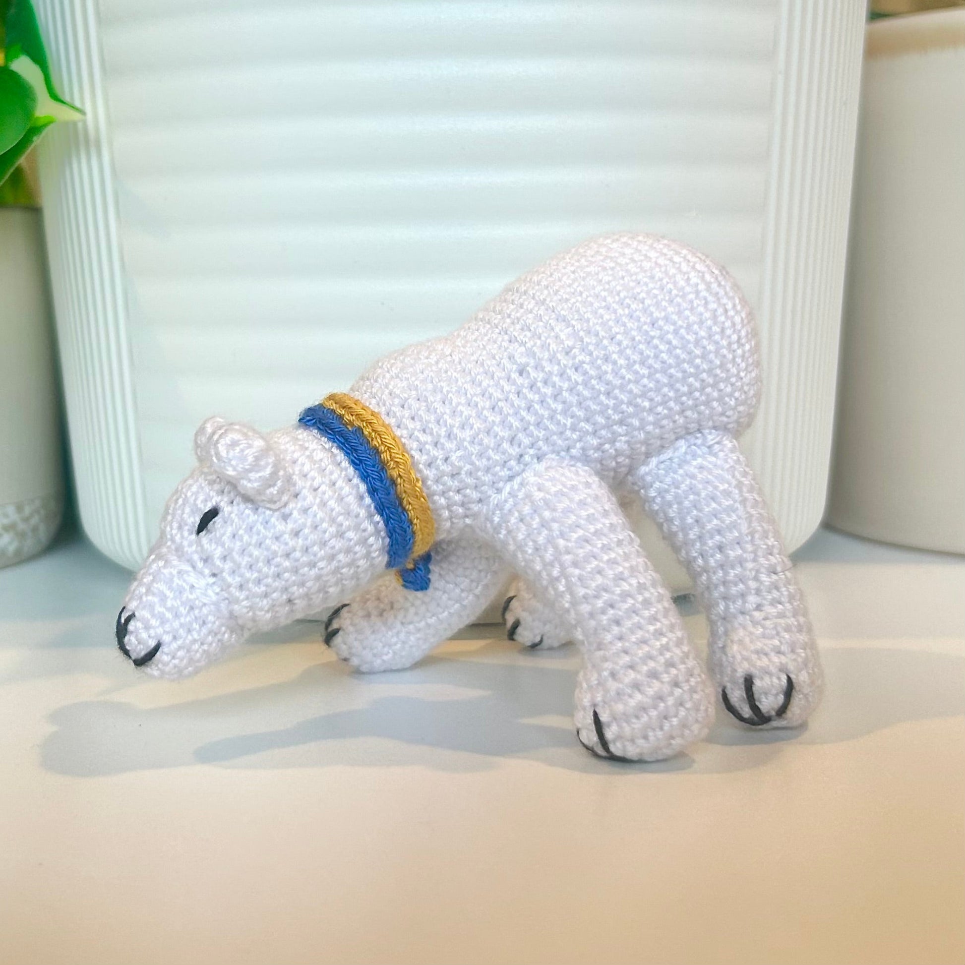 crocheted white polar bear wearing a blue and yellow scarf