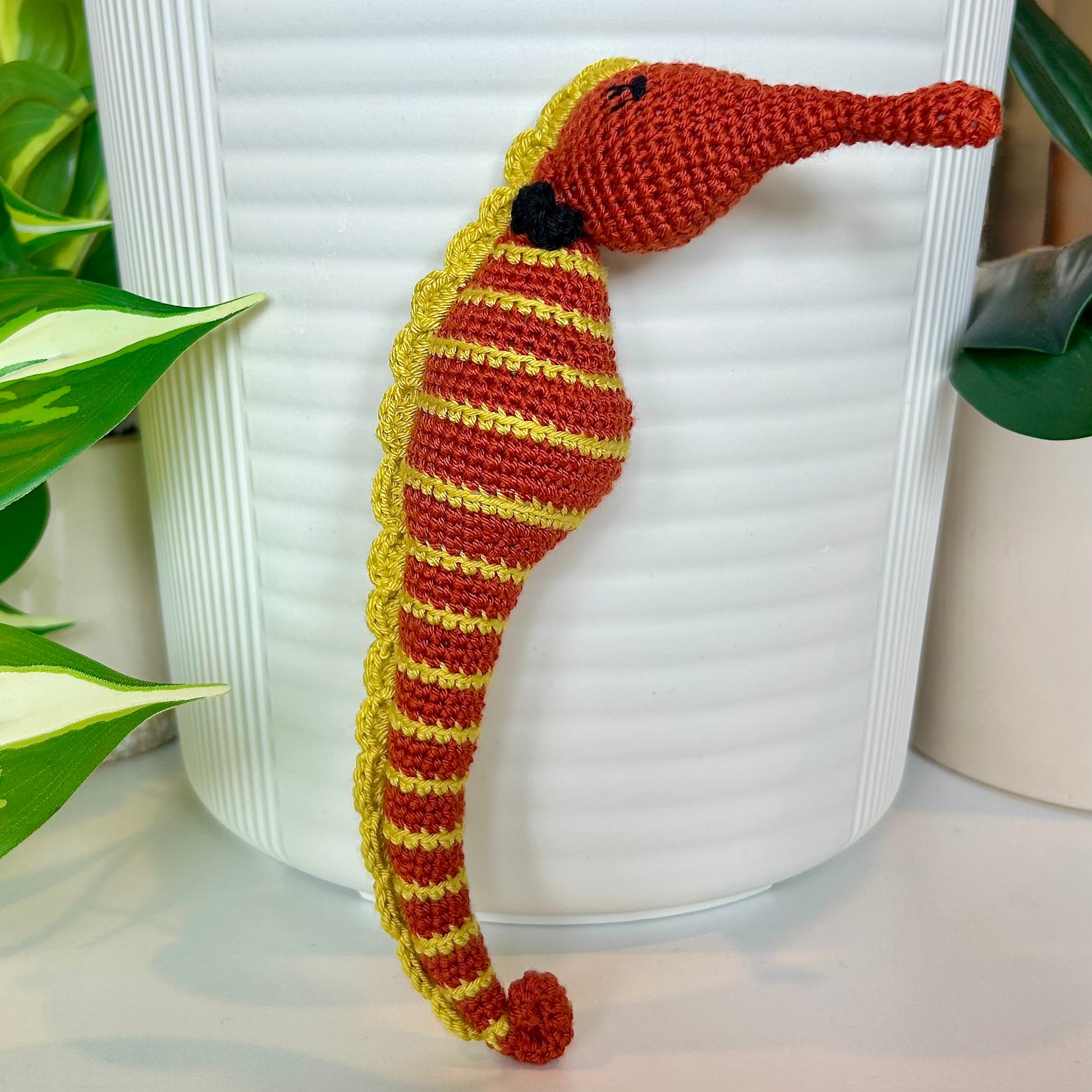 Crocheted terracotta seahorse with chartreuse stripes and a black bow tie