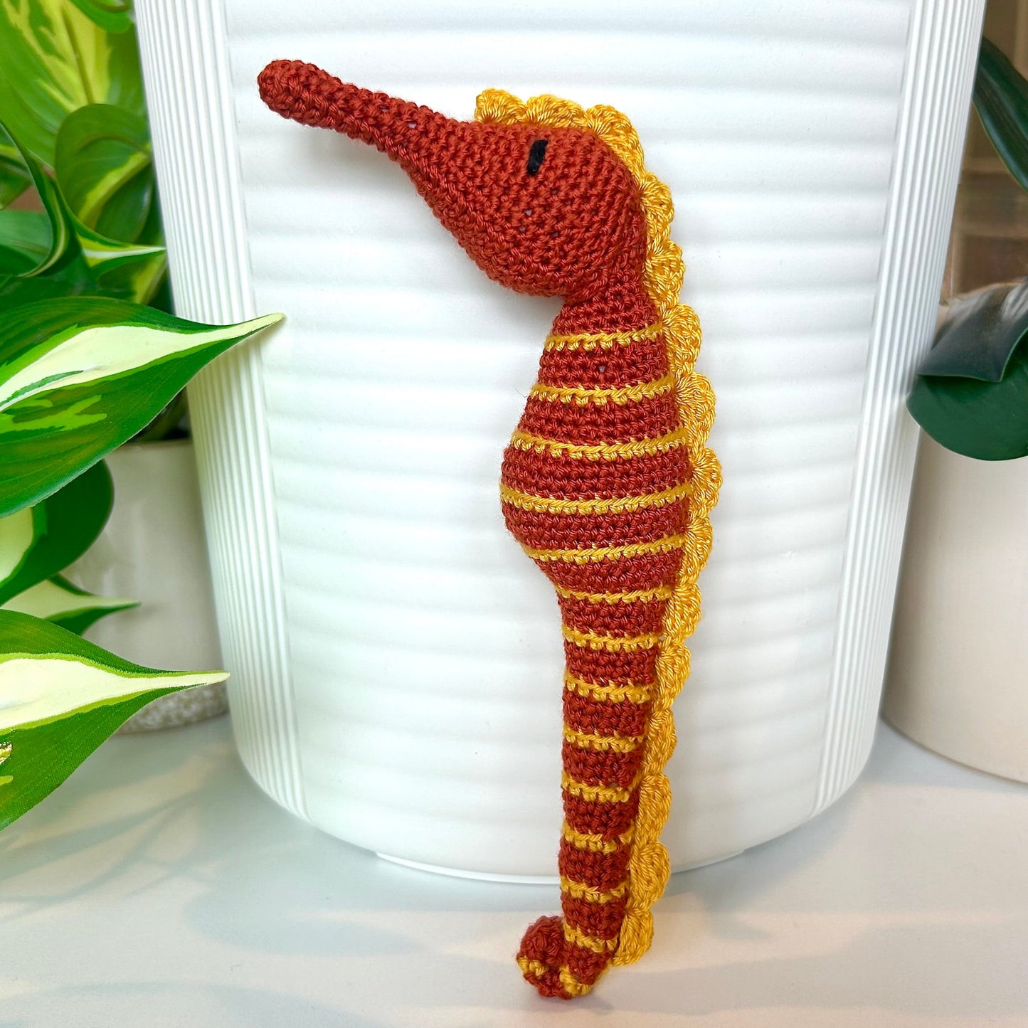 Crocheted terracotta seahorse with sunflower colored stripes