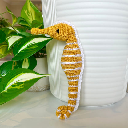crocheted sunflower colored seahorse figurine with white stripes