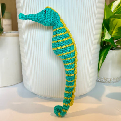 Crocheted turquoise seahorse figurine with chartreuse stripes