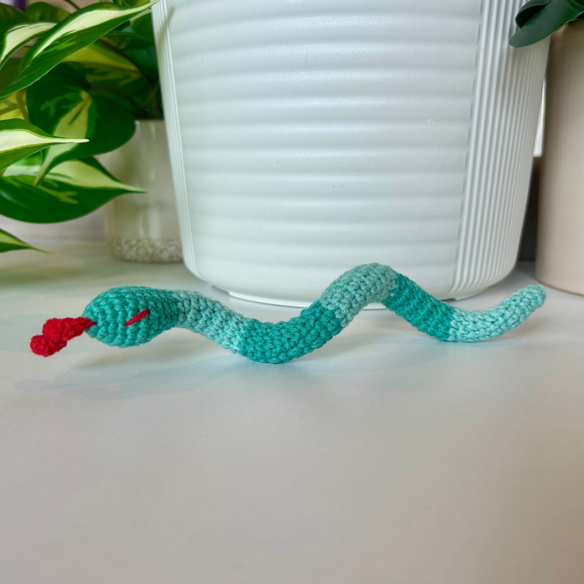 Crocheted snake figurine with aqua stripes and a red tongue 