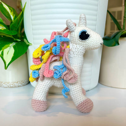 Crochet medium unicorn with pastel pink feet and yellow, blue, and pink mane