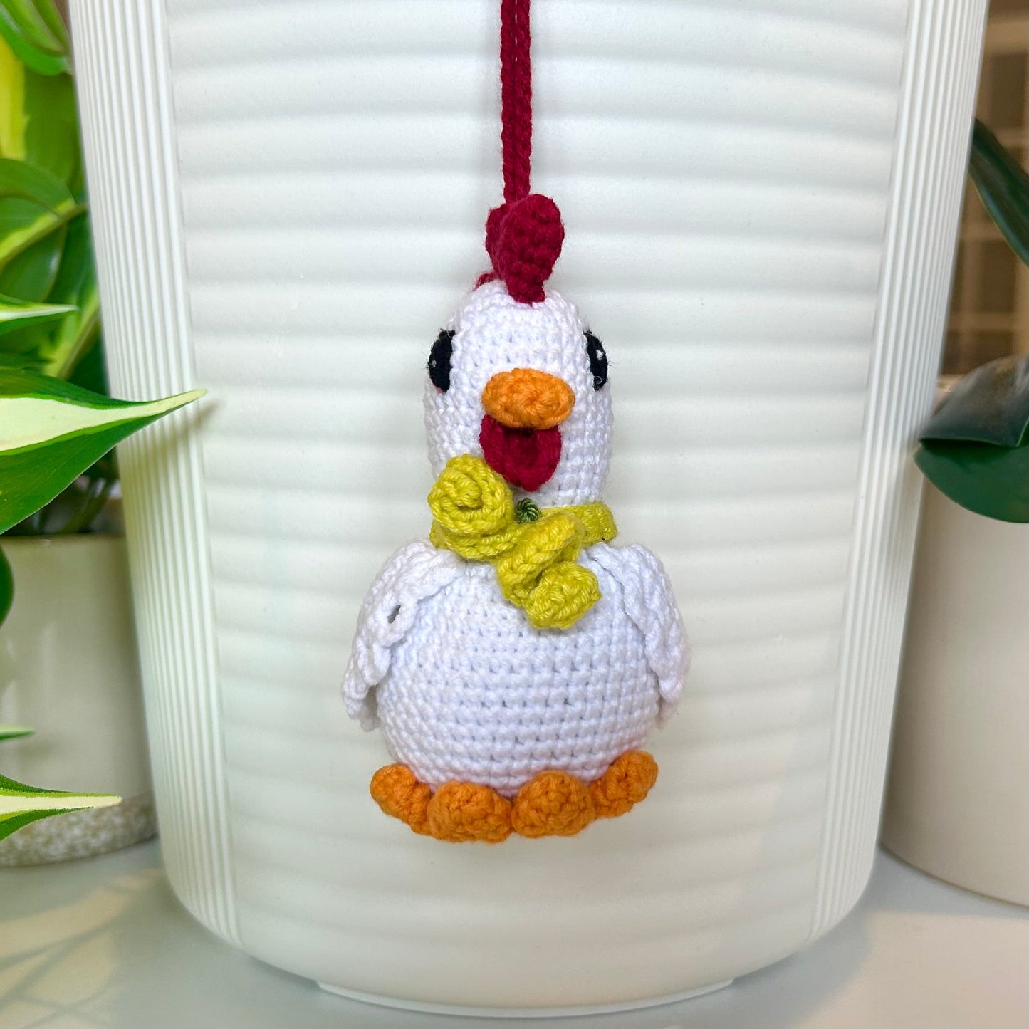 white crocheted chicken charm with a ruby red comb and a curly chartreuse scarf