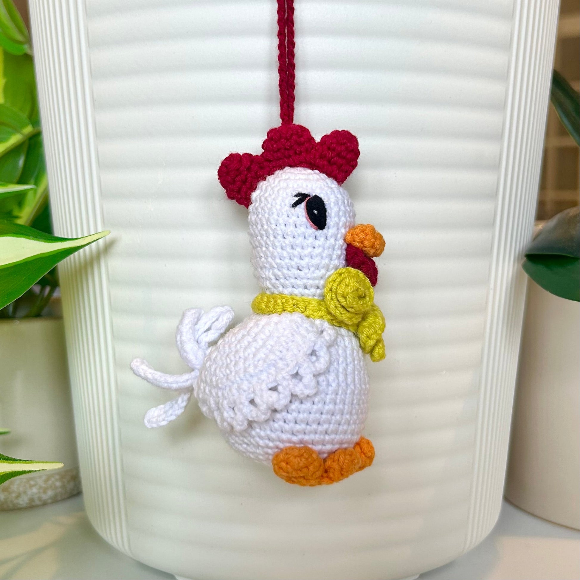 left side profile of white crocheted chicken charm with a ruby red comb and a curly chartreuse scarf