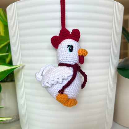 left side profile of white crocheted chicken charm with a ruby red comb and a dark maroon scarf