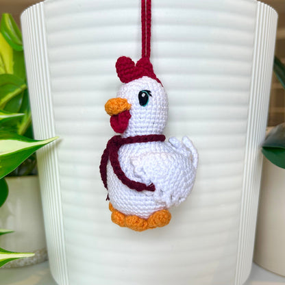 white crocheted chicken charm with a ruby red comb and a dark maroon scarf