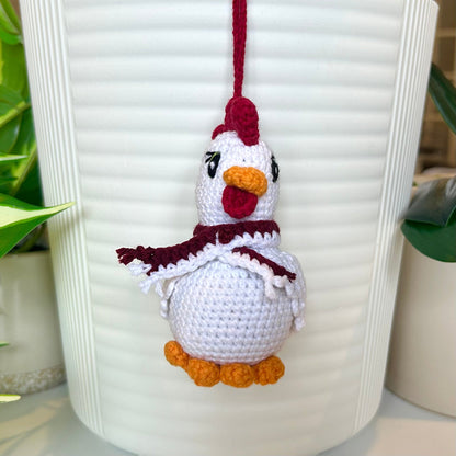 White crocheted chicken charm with a ruby red comb and a dark maroon and white scarf