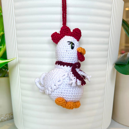 Left side profile of white crocheted chicken charm with a ruby red comb and a dark maroon and white scarf