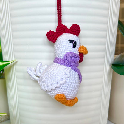 left side profile of white crocheted chicken charm with a ruby red comb and a curly lavender scarf