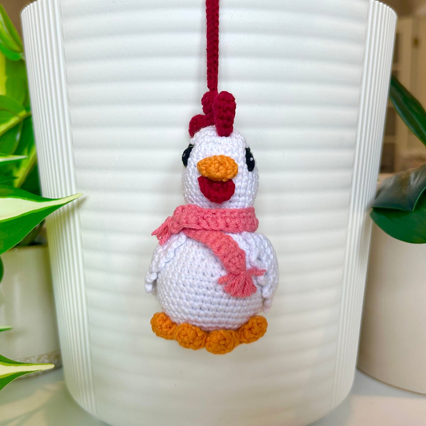 white crocheted chicken charm with a ruby red comb and a light carmine pink scarf