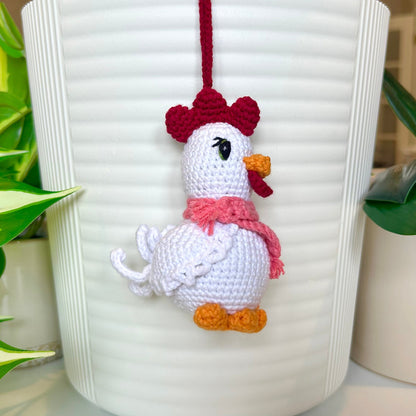 Left side profile of white crocheted chicken charm with a ruby red comb and a light carmine pink scarf