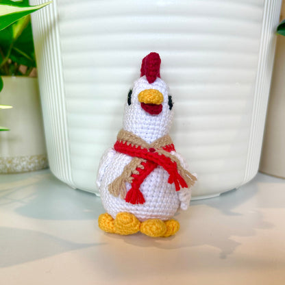 White crocheted chicken charm with a ruby red comb and a red and tan scarf