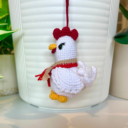 Right side profile of white crocheted chicken charm with a ruby red comb and a red and tan scarf