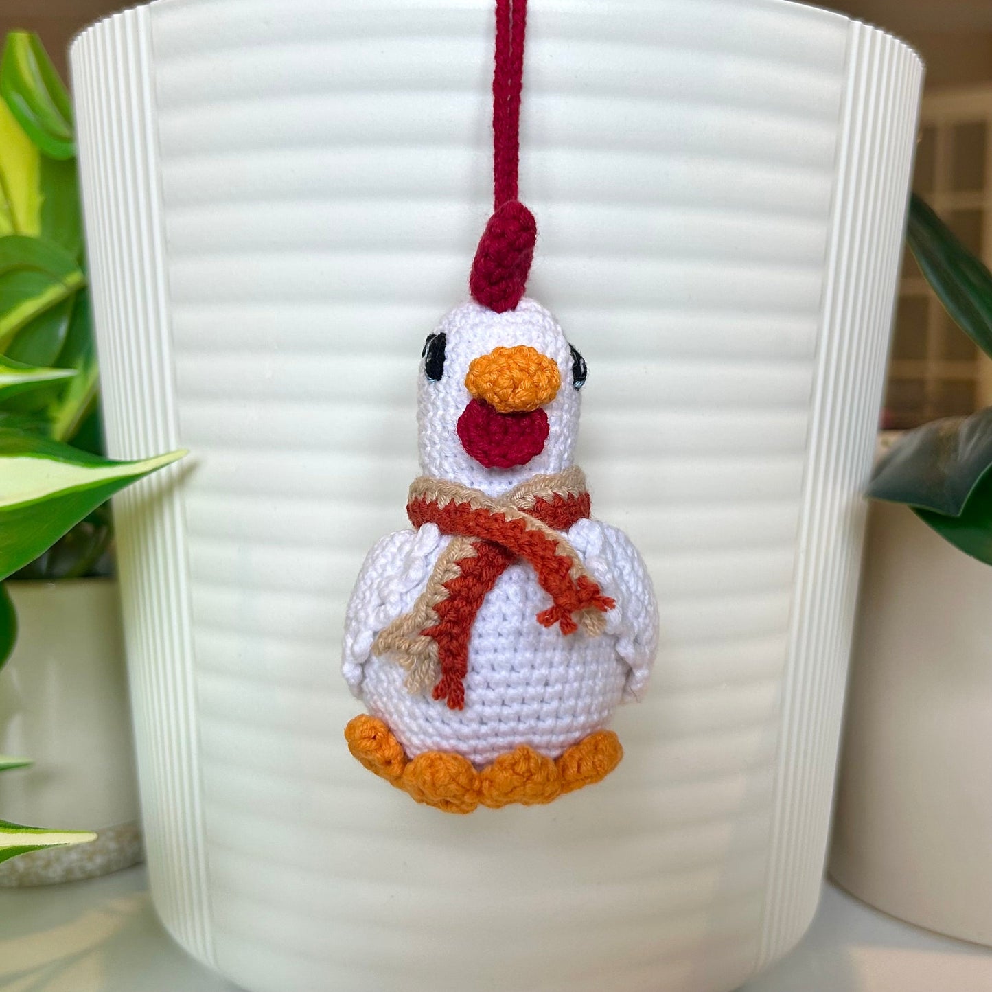white crocheted chicken charm with a ruby red comb and a terracotta and tan scarf