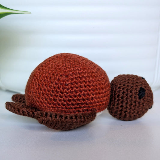 Crocheted sea turtle plush with brown body and terracotta colored shell